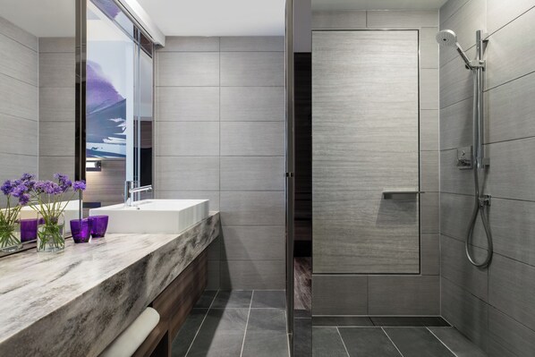 Un baño moderno con un espejo grande, una encimera de mármol y una zona de ducha.