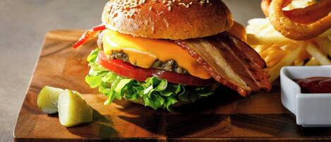 A burger with bacon, cheese, lettuce, and tomato on a bun, accompanied by fries and a side of ketchup.