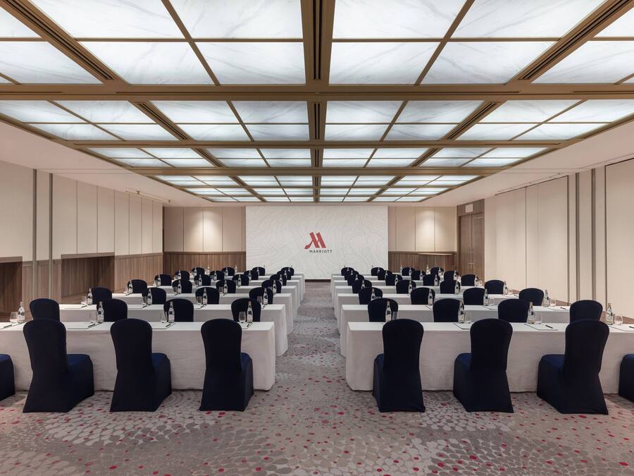 A conference room with a high ceiling, multiple tables, and chairs arranged for meetings.