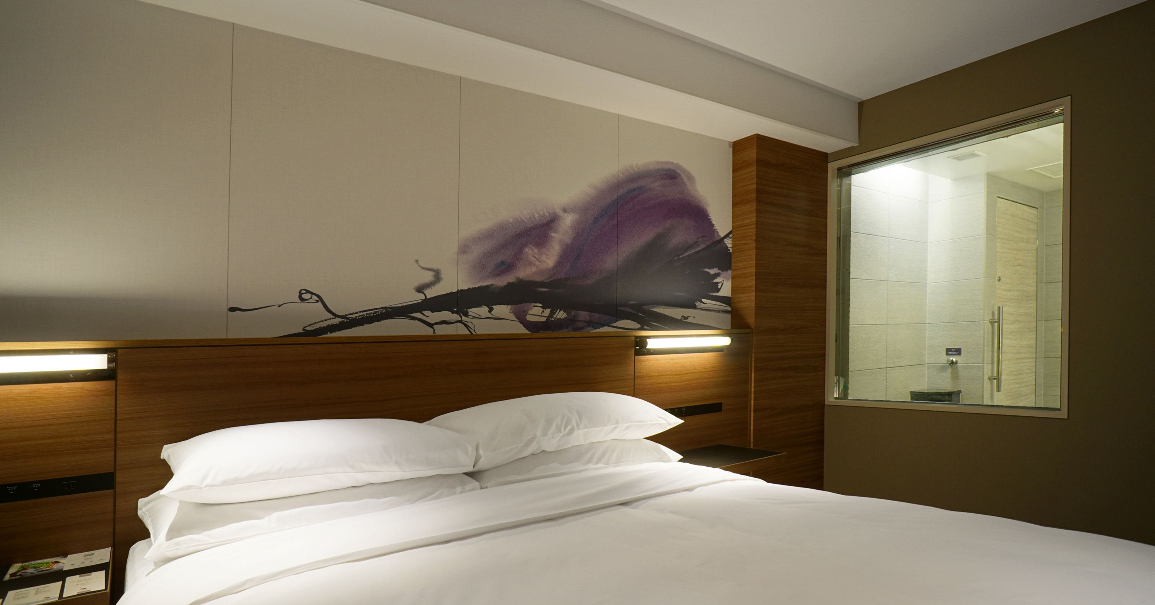Une chambre d’hôtel avec un lit, un grand miroir et une œuvre d’art accrochée au mur.