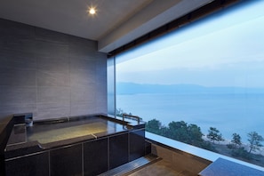 A modern bathroom with a large bathtub, a view of the sea, and a minimalist design.