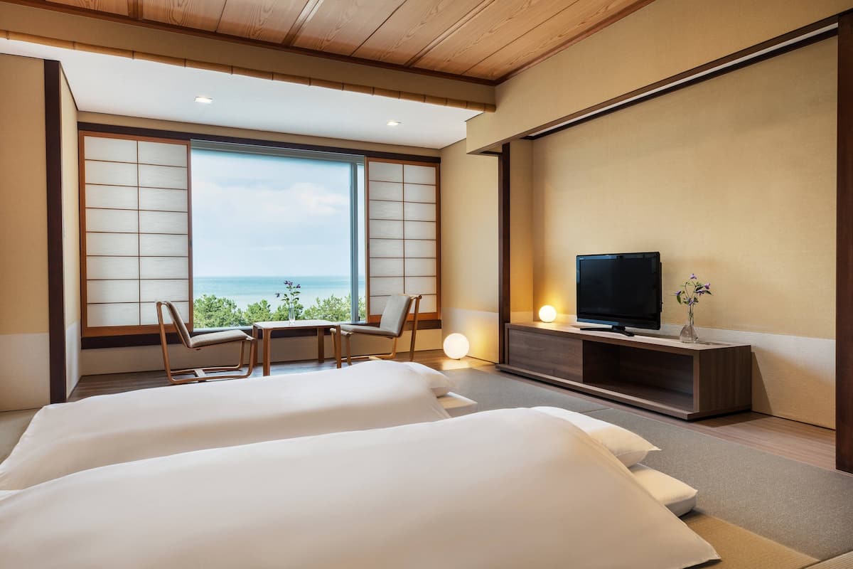 Une chambre d’hôtel avec deux lits, une télévision, un bureau et vue sur la mer.