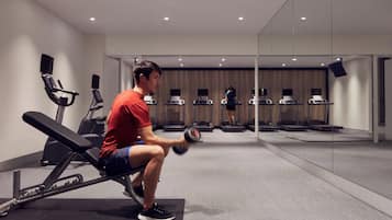 A gym with a man performing a seated dumbbell exercise.