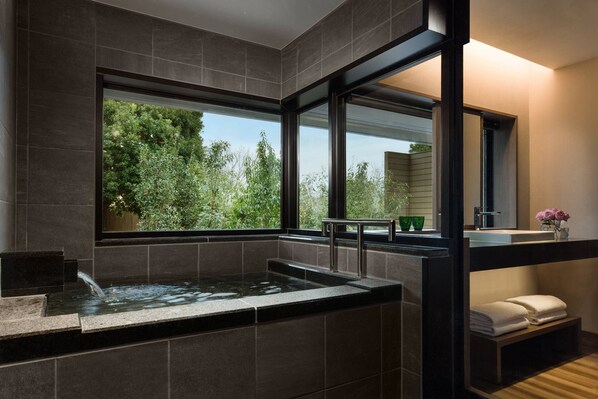 A modern bathroom with a large window, a bathtub, and a vanity with a mirror.