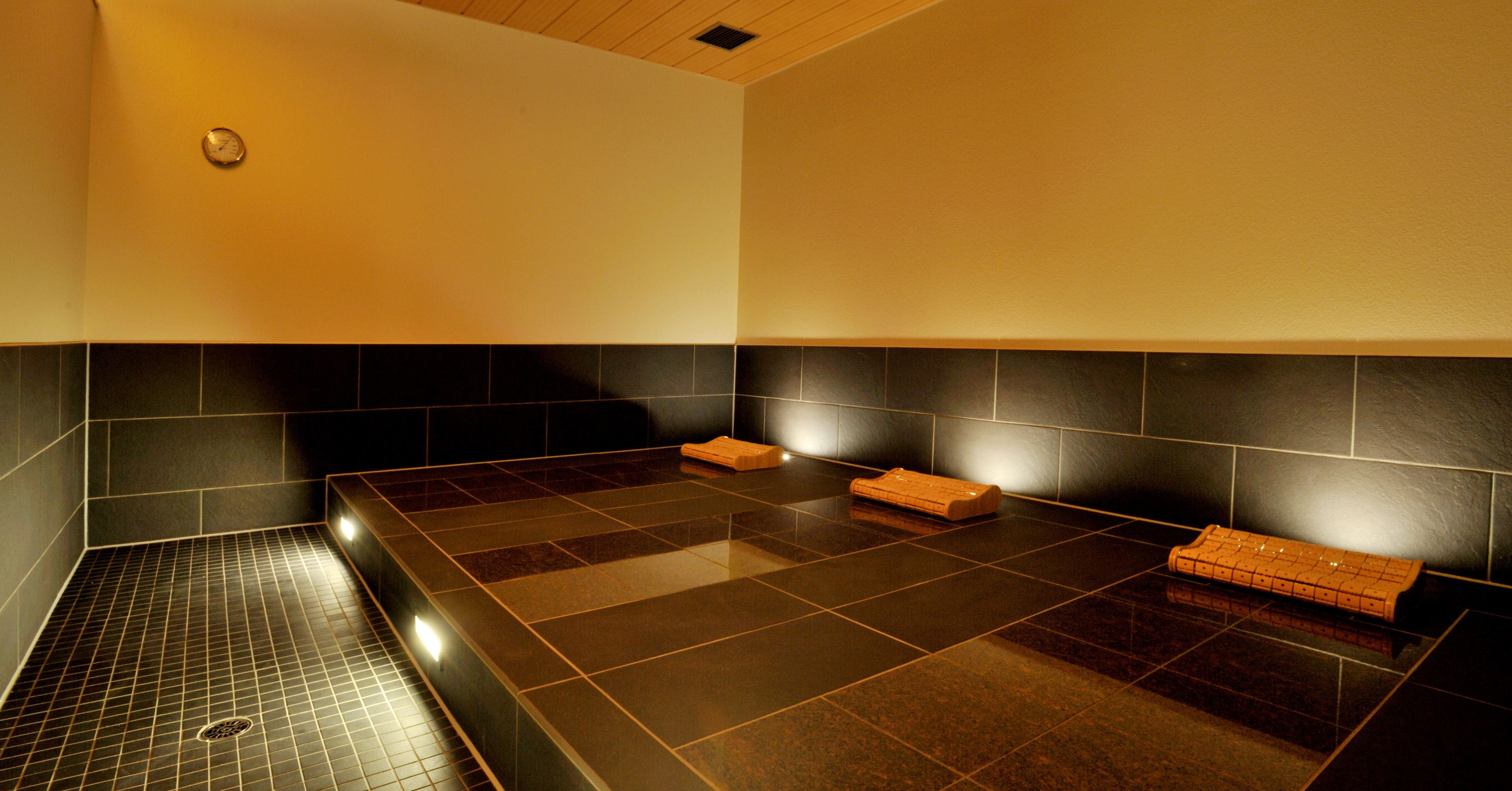 A sauna room with a tiled floor, a bench, and a towel rack.