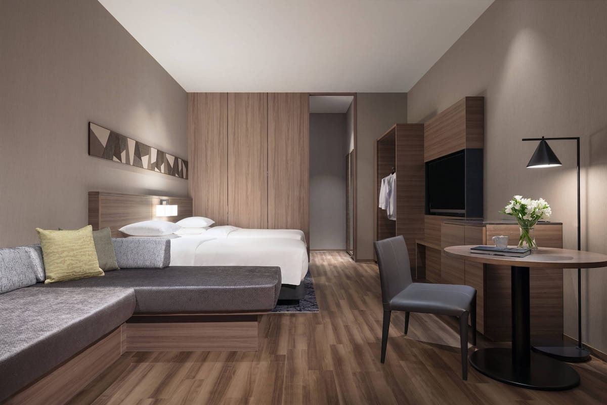 Ein modernes Hotelzimmer mit einer Couch, einem Bett, einem Schreibtisch und einem Sessel.