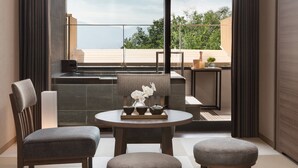 Een moderne kamer met een groot raam, een ronde tafel met een theeservies, een stoel en een bank.