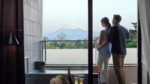 Een stel staat op een balkon met uitzicht op een berg.