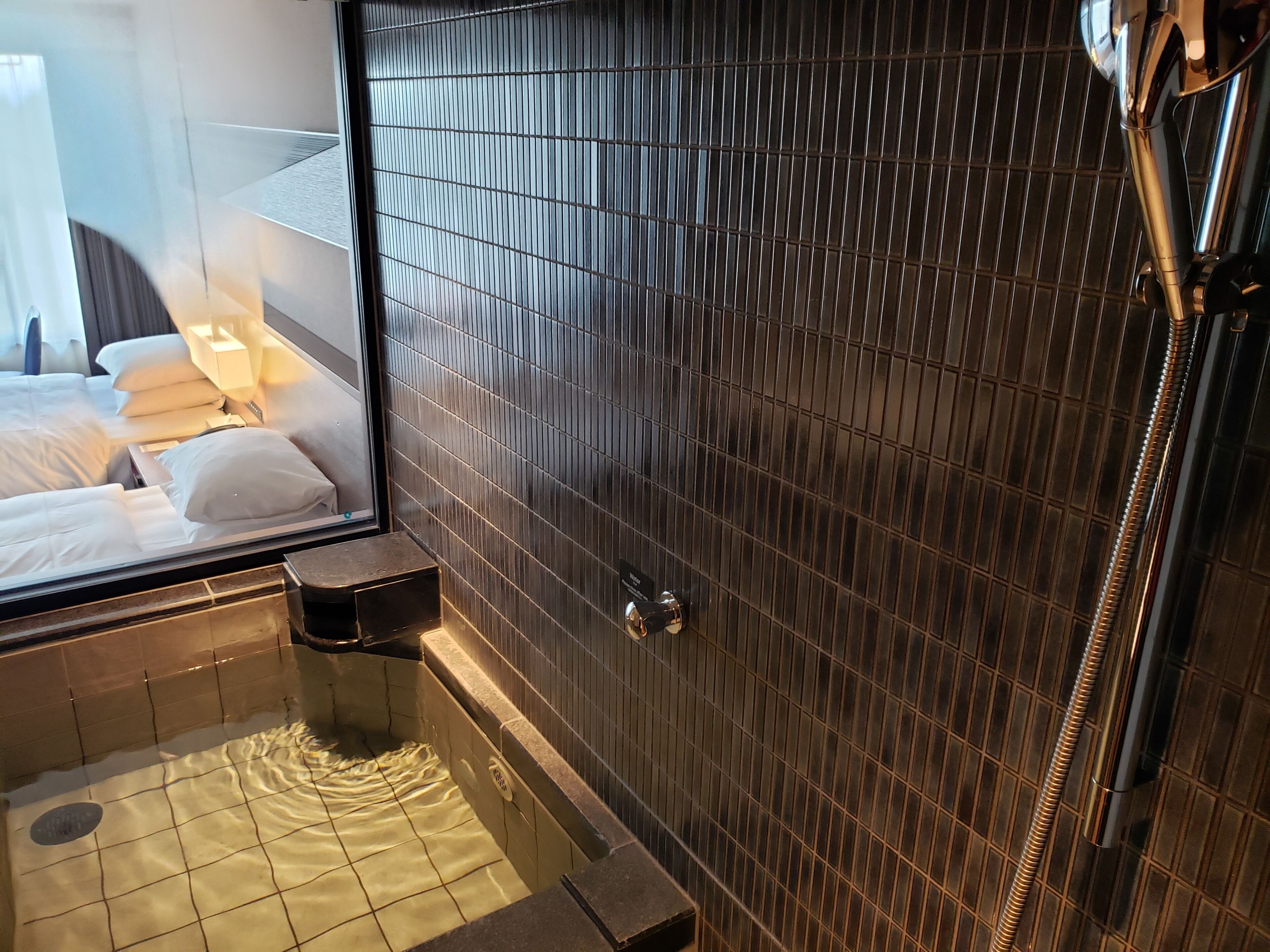 A modern bathroom with a large mirror, a bathtub, and a shower area.