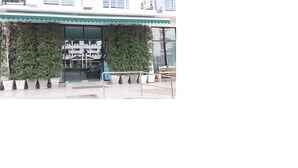A building with a green awning, a glass entrance, and a bench outside.