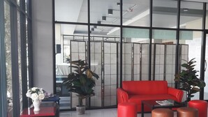 A modern lobby with a red sofa, a coffee table, and potted plants.