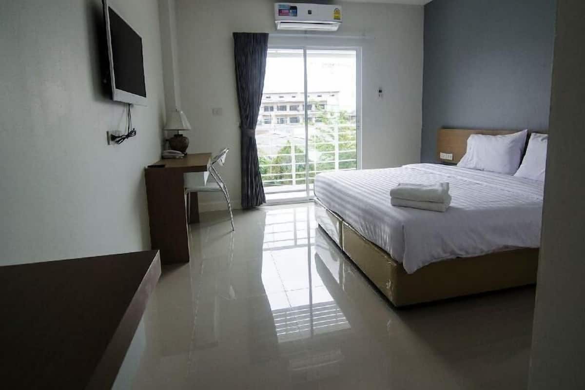 A hotel room with a bed, a desk, a chair, a TV, and a window with curtains.