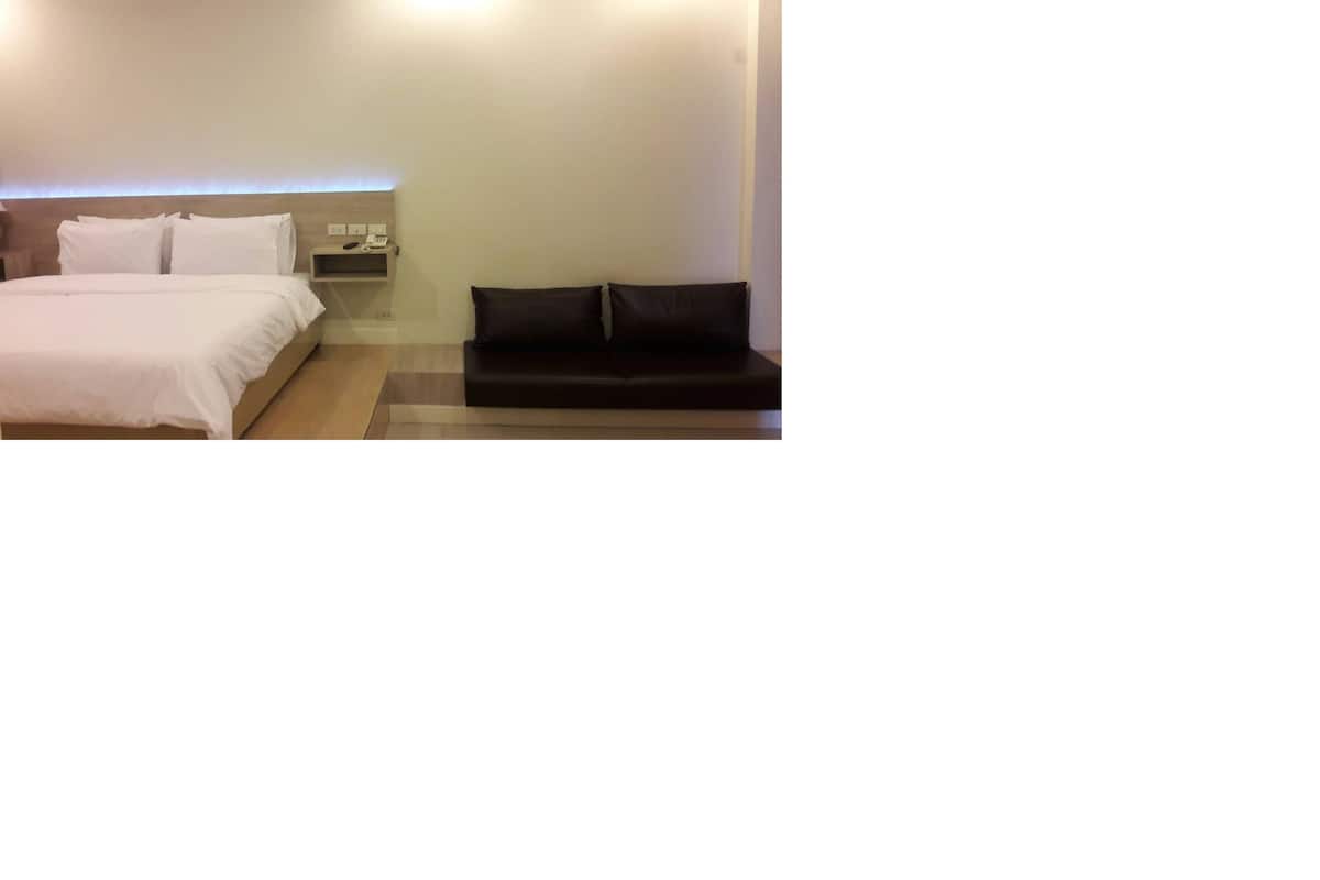 A hotel room with a bed, a nightstand, and a black sofa.