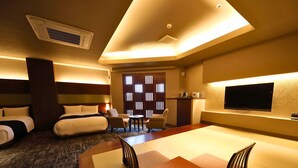 A hotel room with two beds, a desk, a TV, and a seating area.
