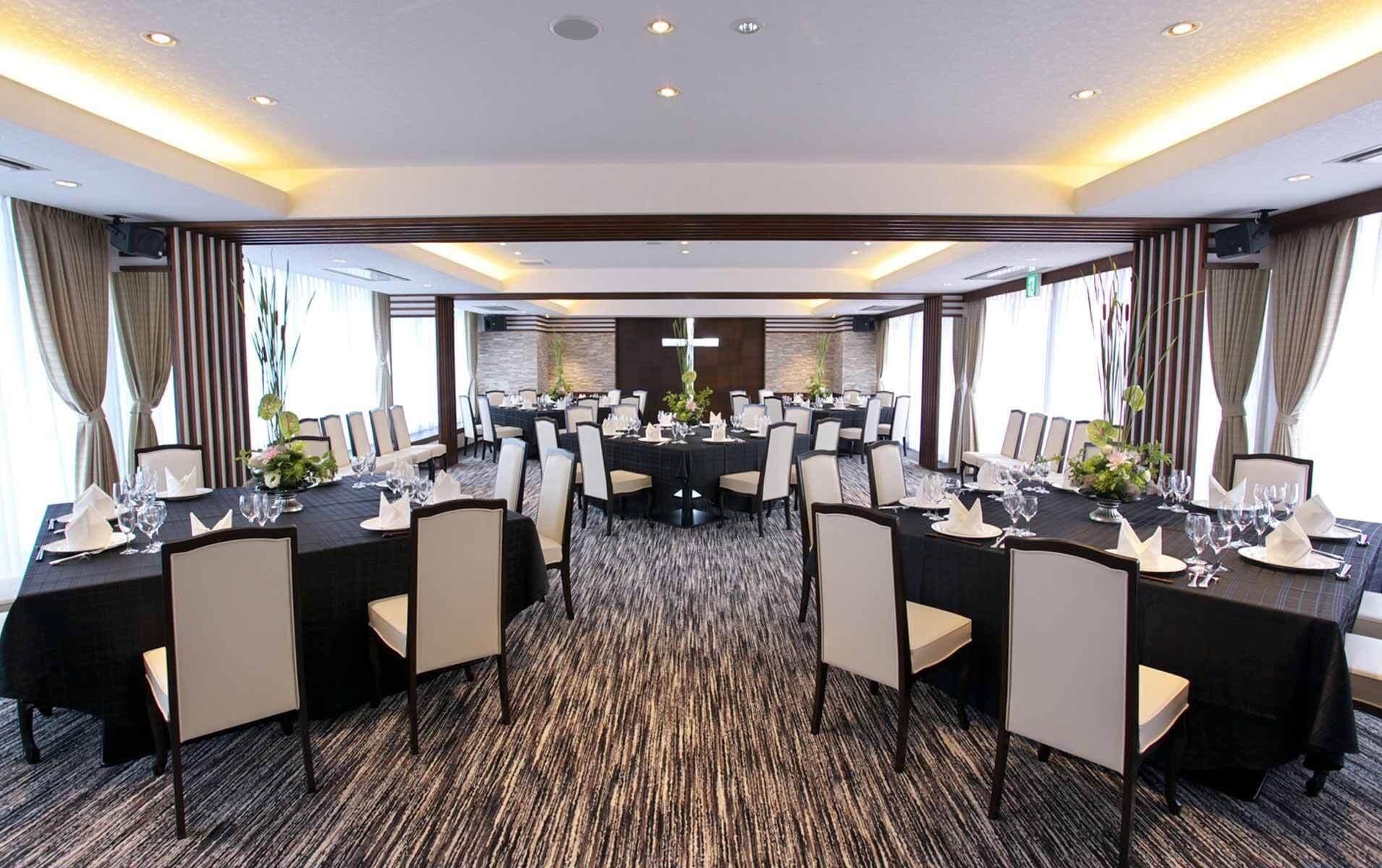A conference room with round tables, chairs, and a carpeted floor.