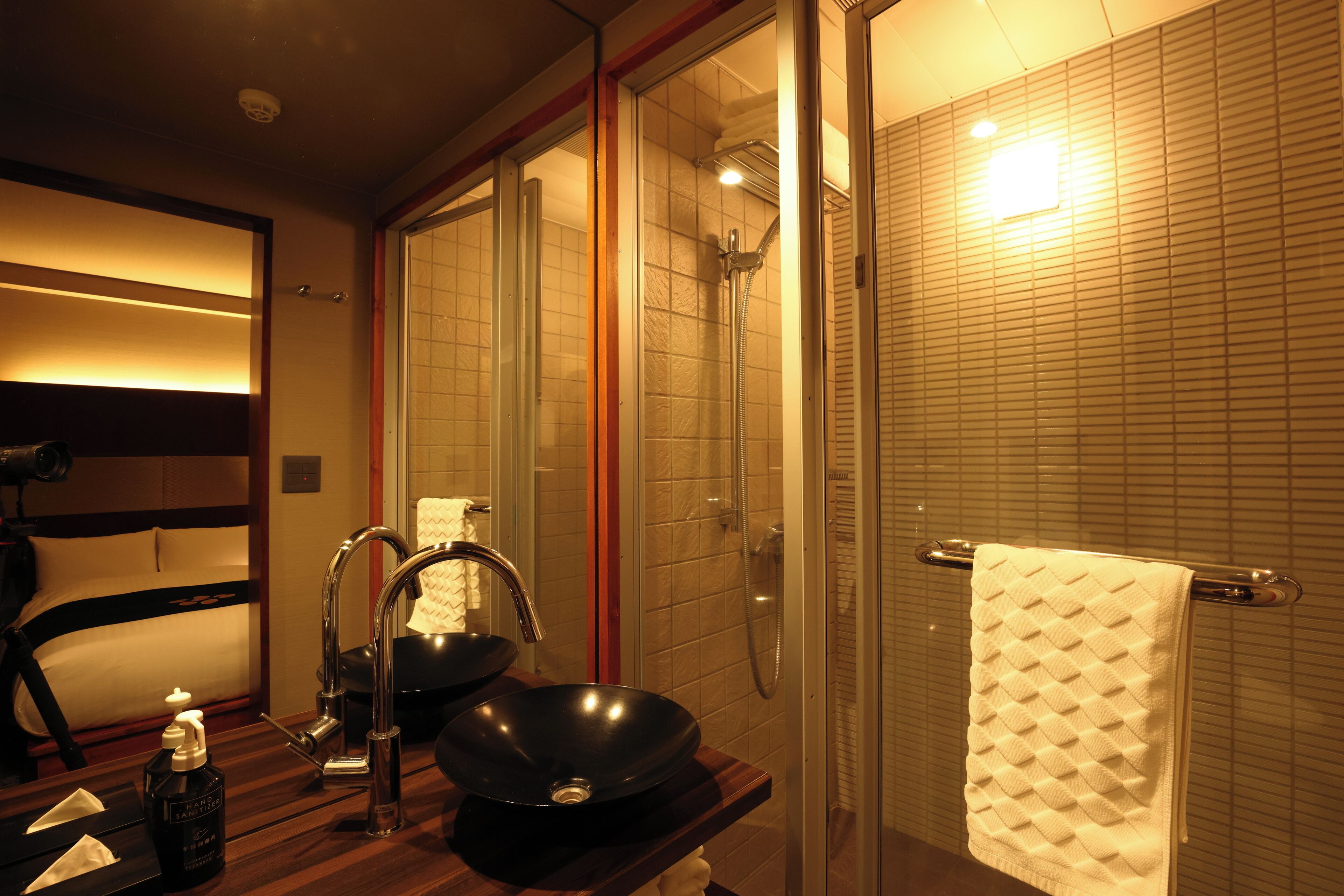 A modern bathroom with a black vessel sink, a glass-enclosed shower, and a towel rack.