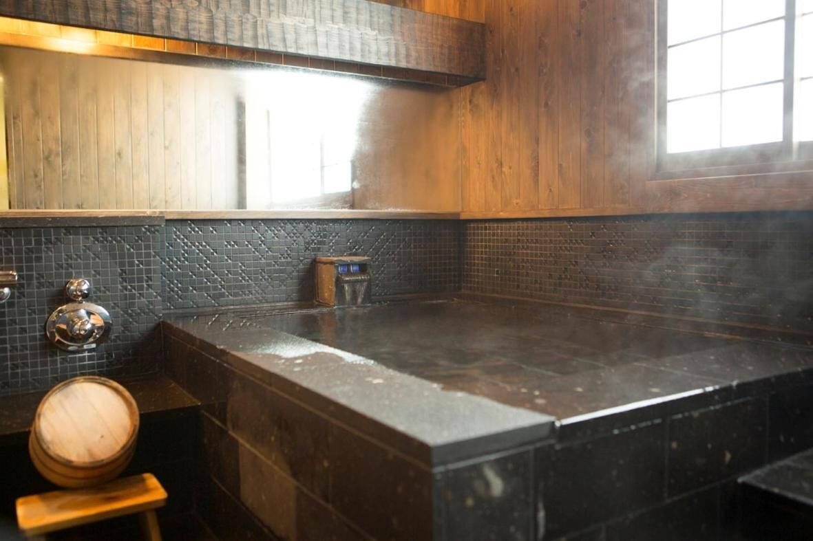 A wet, tiled kitchen with a wooden countertop and a visible stove.