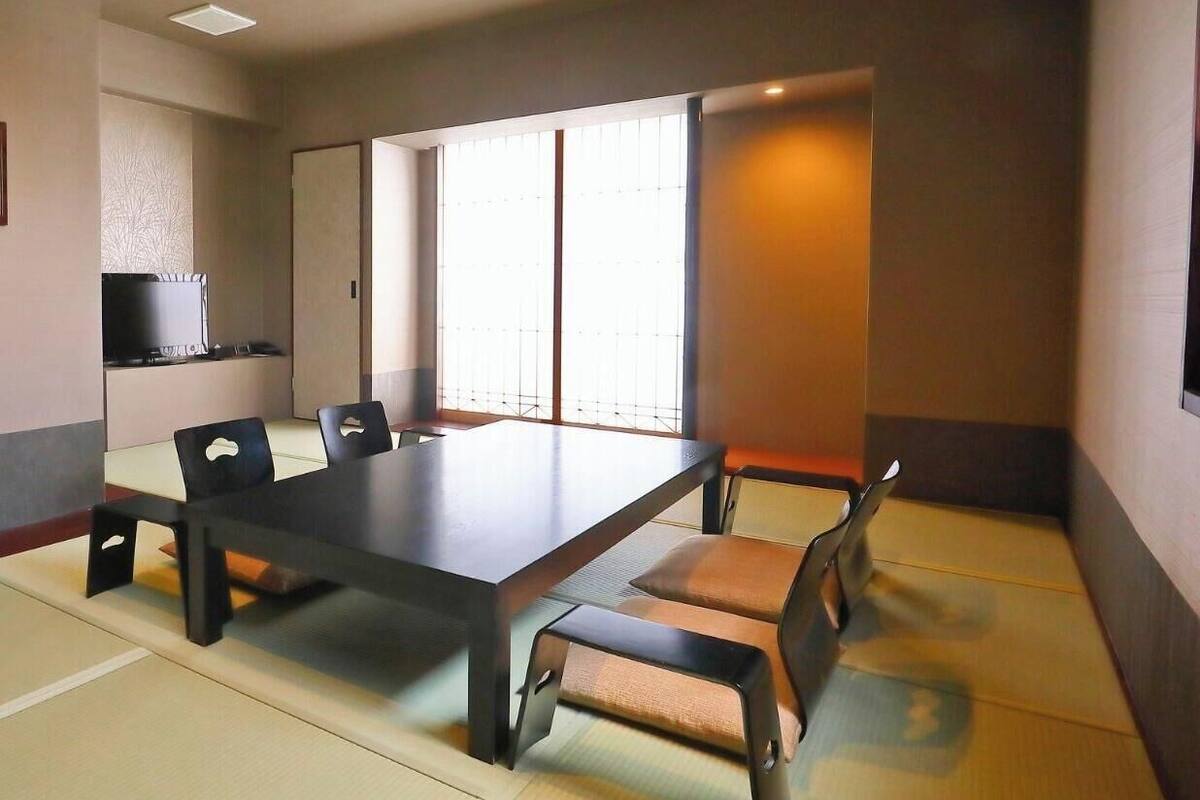 Une pièce de style traditionnel avec un sol recouvert de tatamis, une petite table basse et un téléviseur posé sur une étagère.