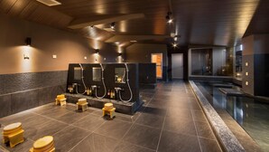 Un baño moderno con un espejo grande, varios lavamanos y una zona de piscina.