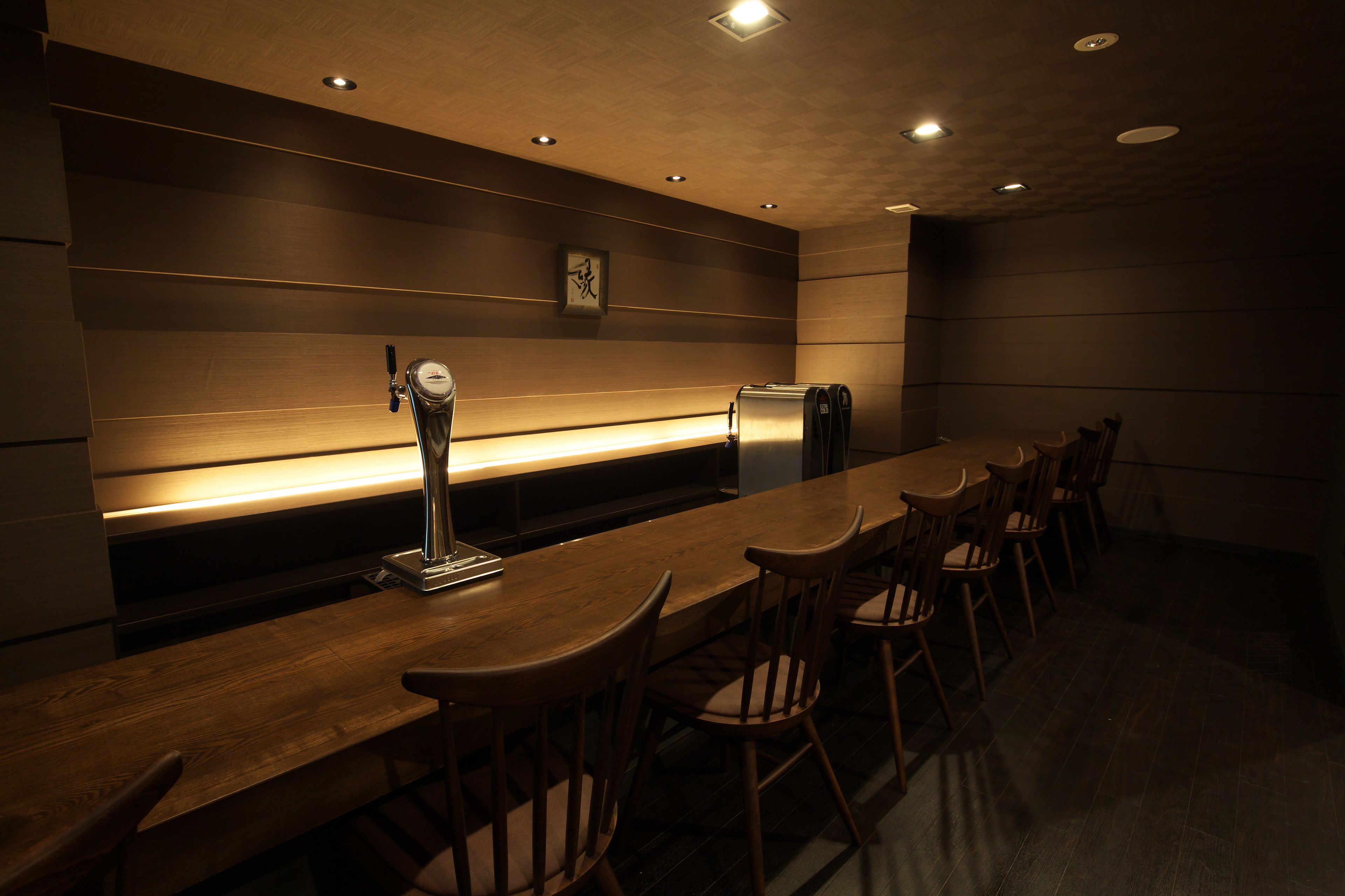 A conference room with a long wooden table, several chairs, a clock on the wall, and a trash bin.