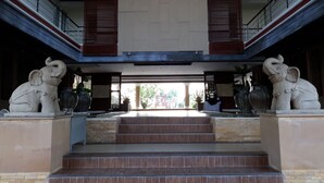 A building entrance with two elephant statues, a staircase, and a covered area with a view of greenery outside. - Beachfront Family Penthouse Hua Hin (Hua Hin)