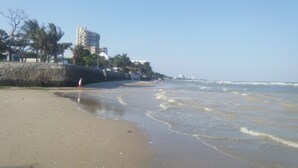 A beach with a stone wall, a few people, and buildings in the background. - Beachfront Family Penthouse Hua Hin (Hua Hin)