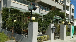 Un edificio de varios pisos con entrada protegida por un portón, una oficina postal y un semáforo.