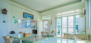 Habitación luminosa con una mesa de vidrio, sillas, un reloj y una puerta que da al exterior.