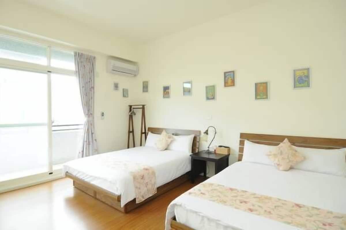 A hotel room with two beds, a large window, and a series of small pictures on the wall.