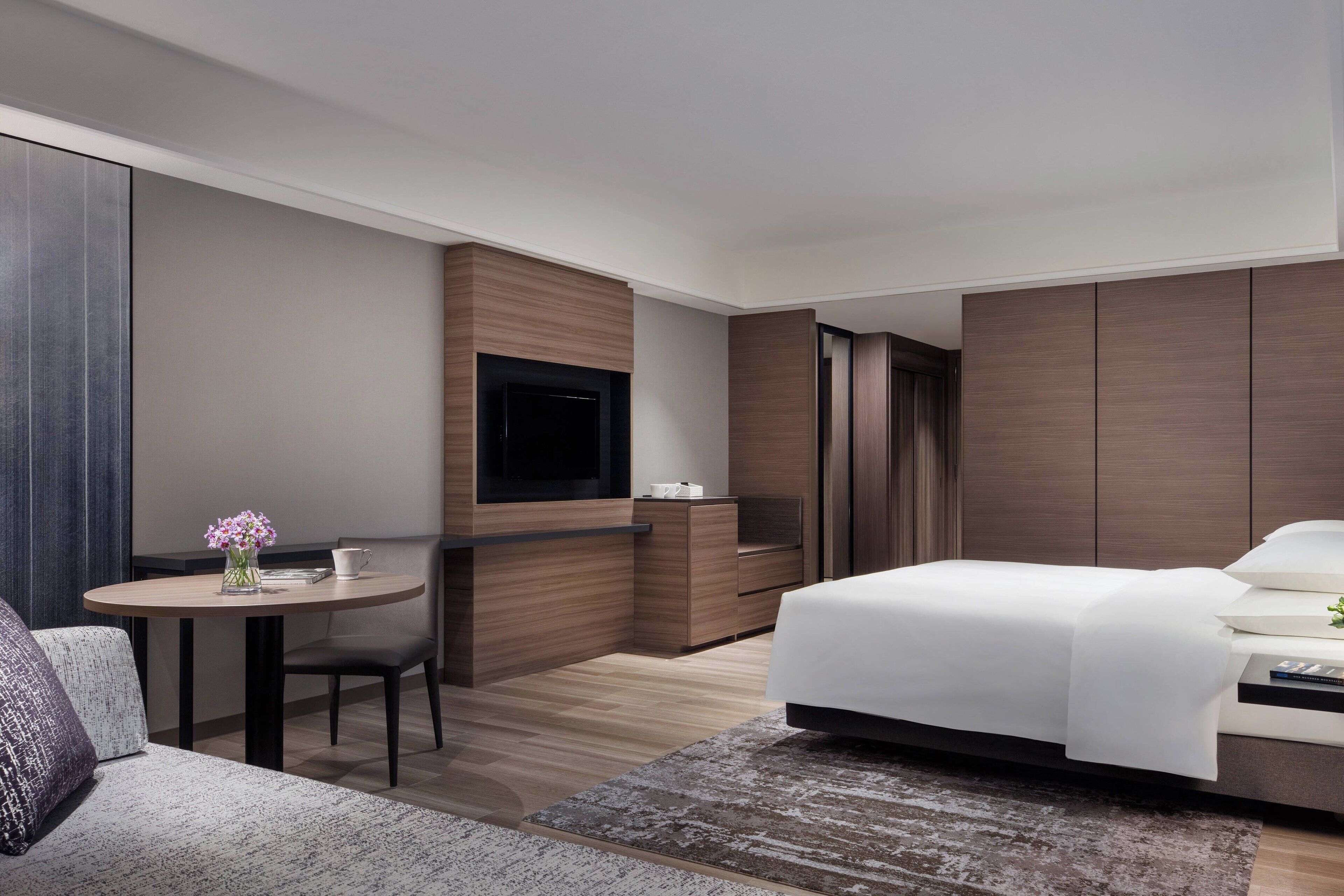 Une chambre d’hôtel moderne équipée d’un lit, d’un bureau, d’une chaise et d’un téléviseur.