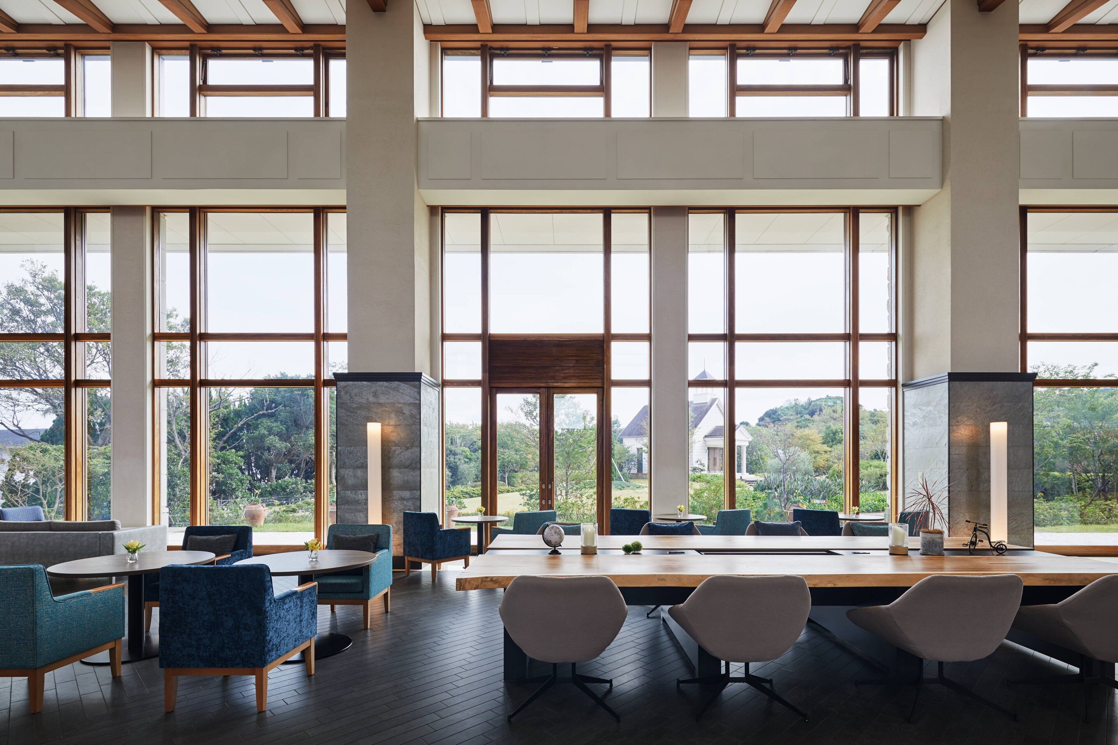 A spacious room with large windows, a wooden ceiling, and a mix of modern and classic furniture.