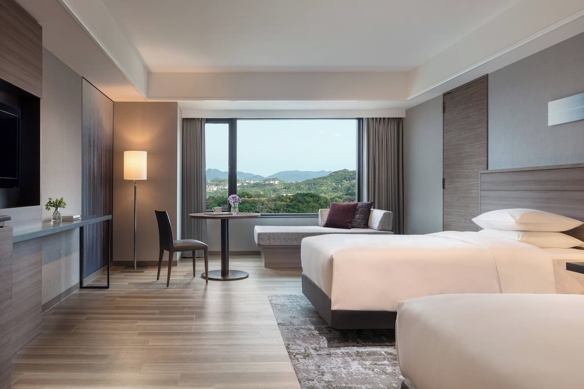 Een moderne hotelkamer met een groot bed, een bureau en uitzicht op de bergen.