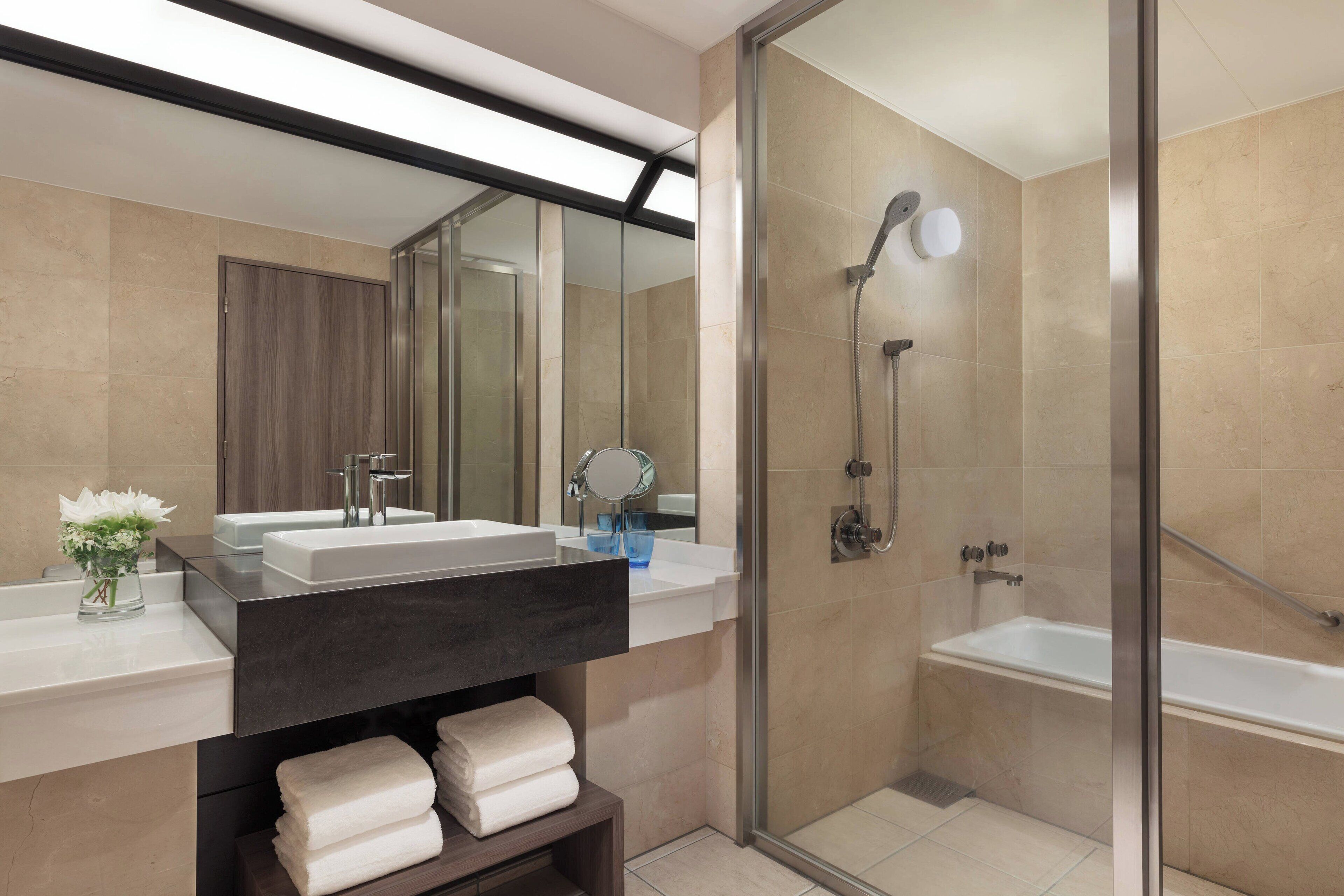 A modern bathroom with a glass-enclosed shower, a vanity with a dark countertop, and a mirror above the sink.