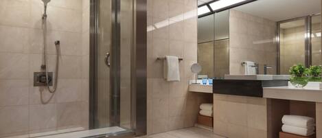 Une salle de bain moderne dotée d’une douche à parois de verre, d’un grand miroir et d’un meuble-lavabo avec un évier et un plan de travail.