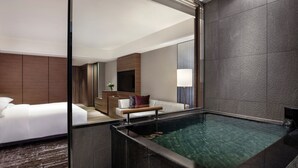 Ein modernes Hotelzimmer mit einem großen Bett, einer kleinen Sitzecke und einer integrierten Whirlwanne.