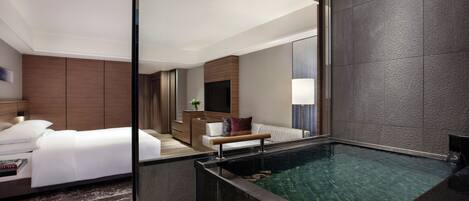 Une chambre d’hôtel moderne dotée d’un grand lit, d’un petit coin salon et d’un jacuzzi intégré.