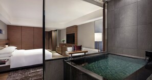 Een moderne hotelkamer met een groot bed, een zithoekje en een ingebouwd bubbelbad.