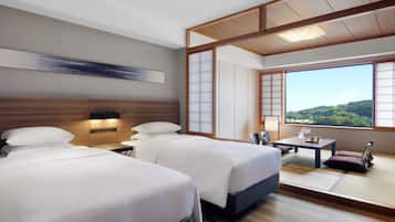 A hotel room with two beds, a desk, and a view of the outdoors.