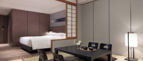 Habitación de hotel moderna con cama, una mesa de comedor con sillas, una lámpara y vistas a la ciudad.