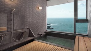 Ein modernes Badezimmer mit einem großen Fenster mit Meerblick, einer Holzbank und einer integrierten Badewanne.