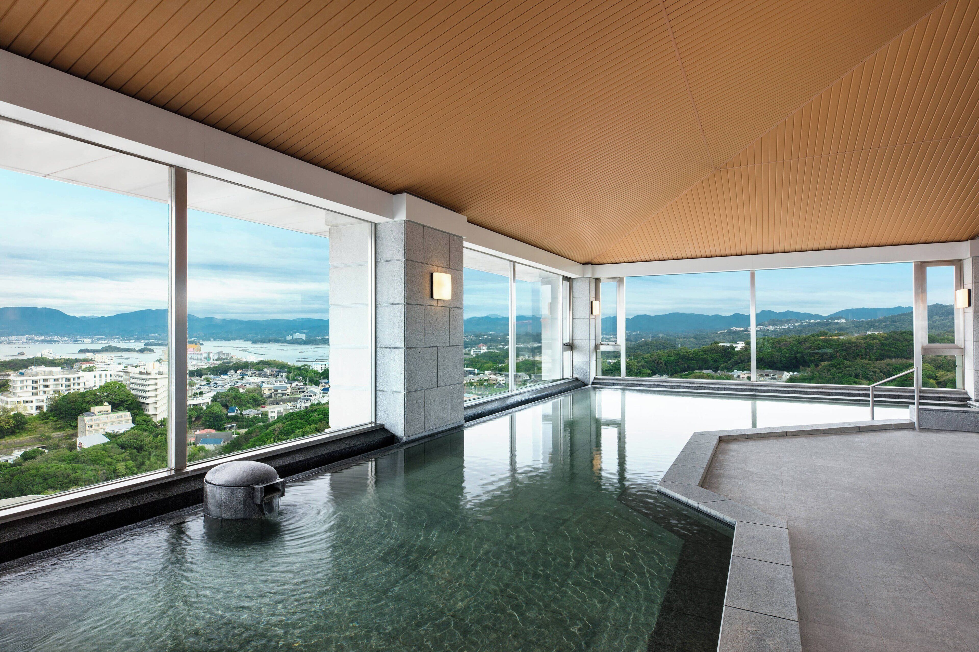 A modern indoor swimming pool with large windows offering a city view.
