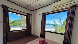 A room with two beds, a window with a view of a beach and palm trees, and an air conditioning unit on the wall. - Phangan Lodge (Ko Pha-ngan)
