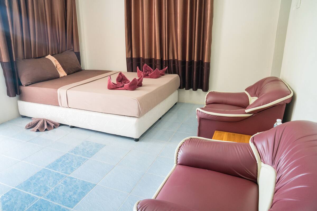 A bedroom with a bed, a massage chair, and a small table.