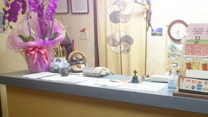 A reception desk with a telephone, a cross, a clock, and various informational brochures.