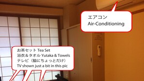 A single room with a bed, a small table with a TV, and an air conditioner.