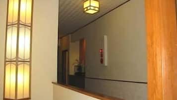 A hallway with a traditional-style wall lantern and a ceiling-mounted light fixture.