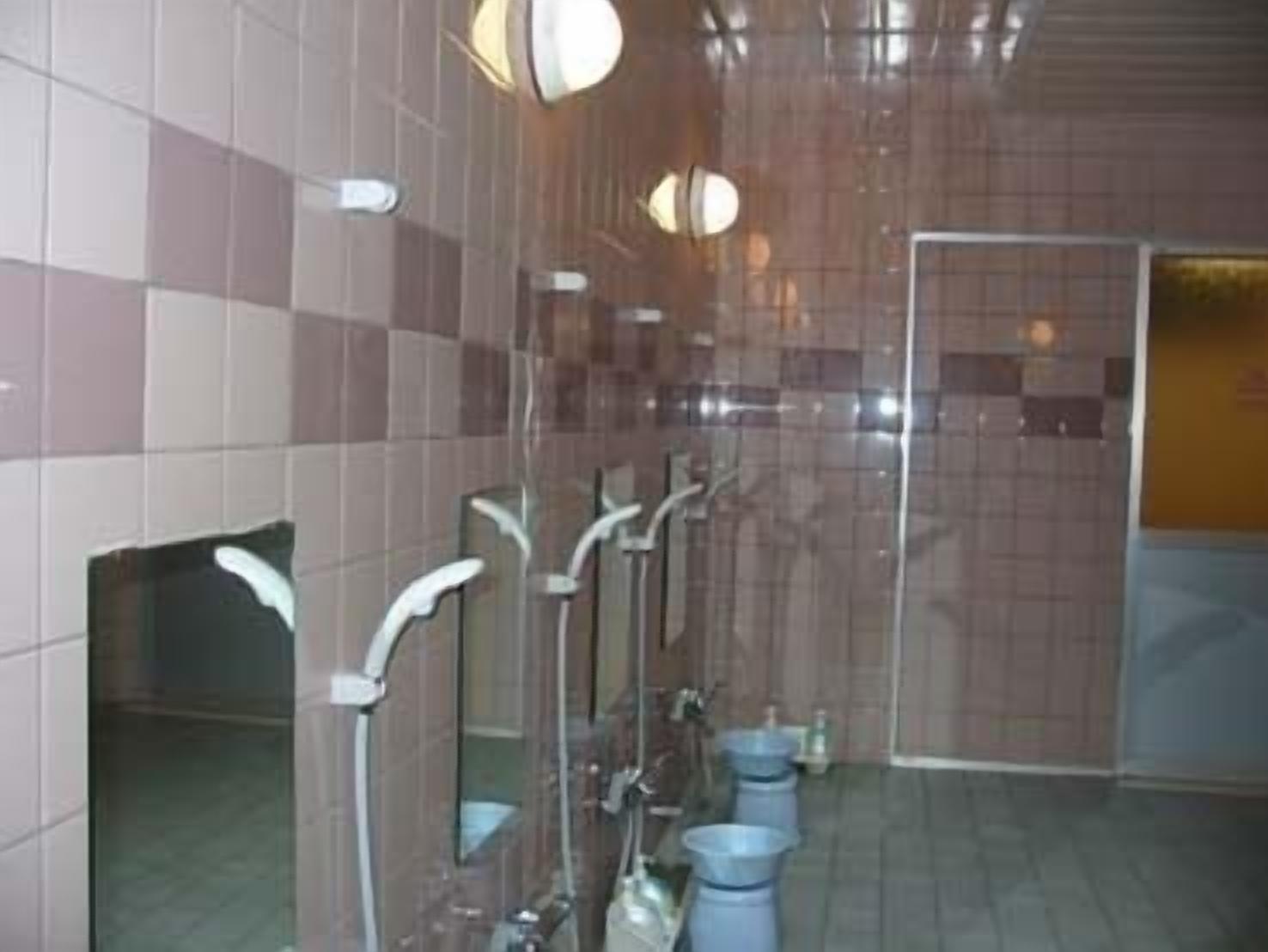 Baño público con varios lavamanos, espejos y suelo de baldosas.