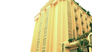 A tall building with a symmetrical facade, featuring vertical columns and decorative elements. - Hotel Mogul Palace (Mumbai)