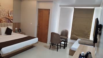 A hotel room with a bed, a desk with a chair, a television, and a door.