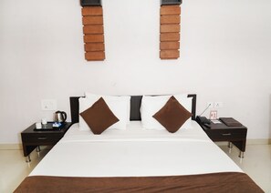 Ett hotellrum med en stor säng, två sängbord, en kaffebryggare, en telefon och ett litet bord med en kopp och en näsdukask.